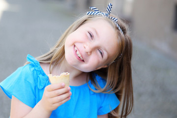 Adorable little girl eating tasty ice cream at park on warm sunny summer day