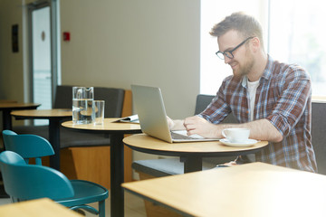 Young designer working online while sitting in cafe