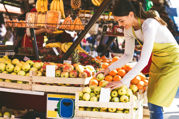 Obraz premium Young attractive fruit market saleswoman sells fresh fruit on the street market.