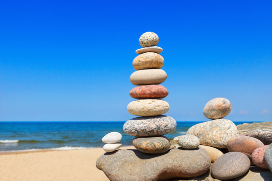 Colored stones balance on a background of blue sky and sea.