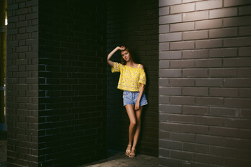 Fototapeta premium pretty cute young woman posing against the wall of black brick