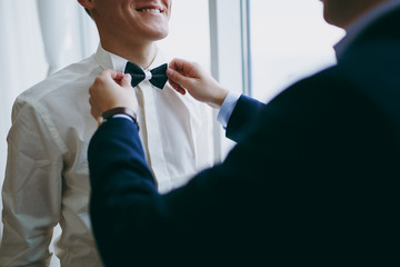 Friend helps the groom to dress in the morning