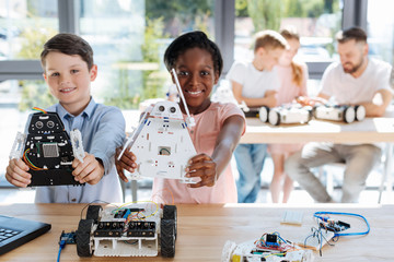 Adorable girl and her friend posing with robot models