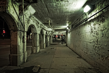 Dark and gritty Chicago urban city street and alley at night. Decaying train bridge and station underpass and sidewalk. - obrazy, fototapety, plakaty