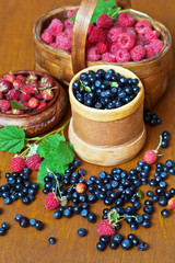 Forest berries: blueberries, raspberries and strawberries on a wooden background. Preparing vitamins for future us