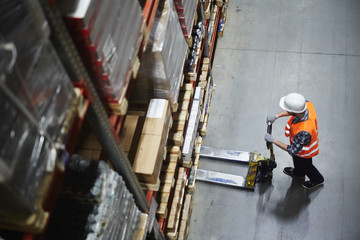 Above view of warehouse loader using forklift cart to pick up pallet with goods