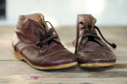Old leather shoes on wooden flor; close up, selective focus.