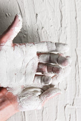 Plastering work, building. Dirty worker hands in white stucco on rough background, flat lay.