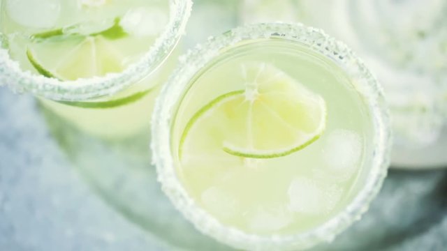 Key lime margarita garnished with fresh lime and salt in mason jar on metal tray