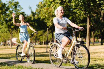 Obraz premium Cheerful senior woman riding bicycles with her granddaughter