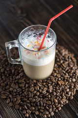 Coffee drink in a transparent mug on a wooden table with cofee grains