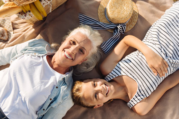 Joyful woman and her granddaughter resting on a picnic