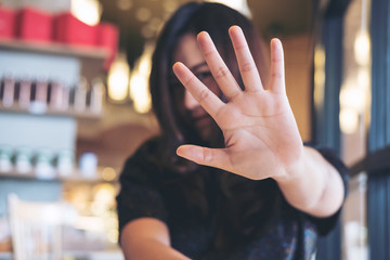 An Asian woman showing her hand sign cover her face to say no to someone with feeling angry in...