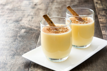 Homemade eggnog with cinnamon on wooden table. Typical Christmas dessert.
