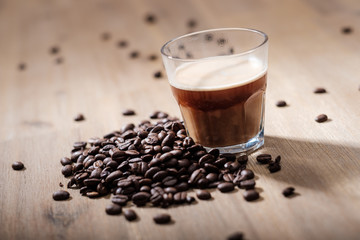 Fresh coffee in a glass with coffee beans on a wood table