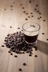 Fresh coffee in a glass with coffee beans on a wood table