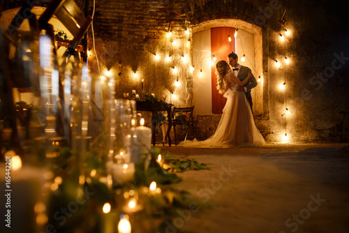 Stylish hipster wedding couple in romantic loft decorations at night