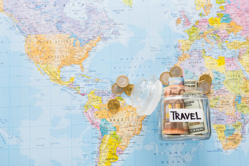 Travel budget concept. Money saved for vacation in glass jar on map background