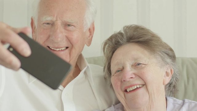 Happy Senior Caucasian couple taking selfies on a smartphone themes of smartphone technology selfie humour seniors