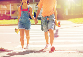 teenage couple with skateboards at city crosswalk