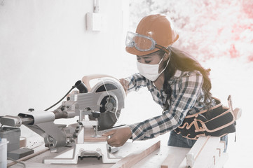 Asian pretty female carpenter using Electric Sander for wood