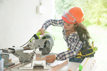 Asian pretty female carpenter using Electric Sander for wood