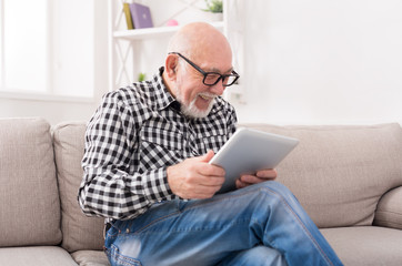 Senior man reading news on digital tablet