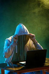 Hooded computer hacker stealing information with laptop