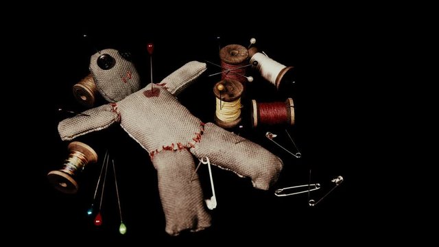 stitched voodoo doll for ritual on a black background with threads and needles