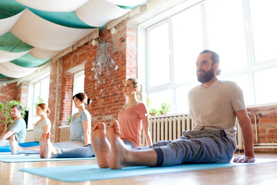 group of people doing yoga staff pose at studio