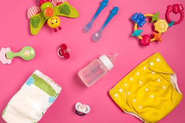 Baby care accessories and diapers on pink background. Top view