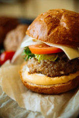 Big sandwich - hamburger with juicy chicken burger, cheese, tomato, and red onion on wooden background