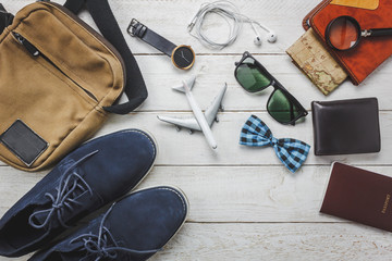 Top view accessories man fashion to travel concept.Airplane and earphone on wooden background.man's shoe,bag,bow tie,map,passport,watch,notebook on wood table.flat lay.copy space.