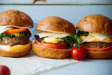 Tasty turkey burgers with corn salad and carrot,mixed seeds served on old board on a rustic wooden table with copyspace.