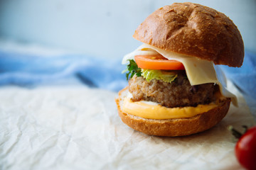 Tasty burger with beef with spinach and blue cheese served on a small board on a wooden background.