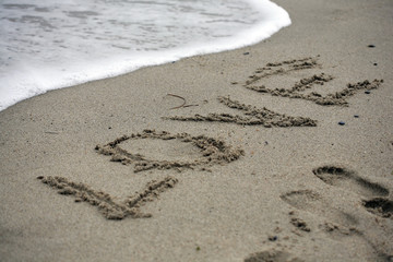 Love message on beach - feelings and sign concept; selective focus background.