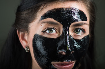 Close up of a beauty young woman using a black mask to clean skin