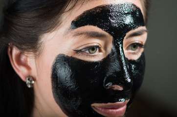 Close up of a beauty young woman using a black mask to clean skin