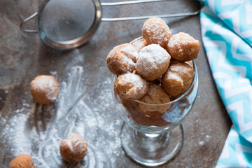 Homemade small donuts with powdered sugar in the glass