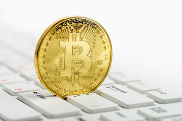 Golden Bitcoin on white keyboard