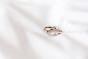 Golden wedding rings on white fabric background. Symbol of love and marriage.