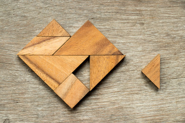 Tangram puzzle in heart shape wait to fulfill with triangle shape on wooden background