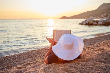 Foto auf Acrylglas Woman reading a book on the beach at sunset © Rostislav Sedlacek