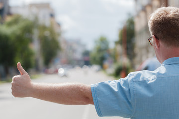 man standing on the city street and hailing a taxi