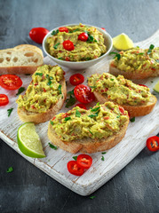 Homemade Guacamole toast with chili pepper, parsley on white wooden board