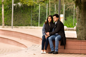 Beautiful young couple in love in st valentines day sitting in a park