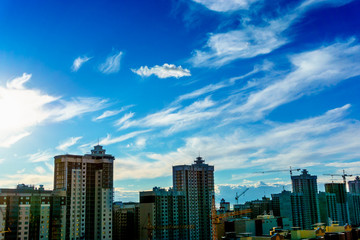 Fototapeta premium New modern buildings and cranes at dramatic sky background