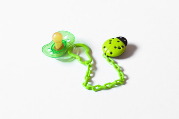 pacifier with chain and holder in the form of green ladybugs on a white background