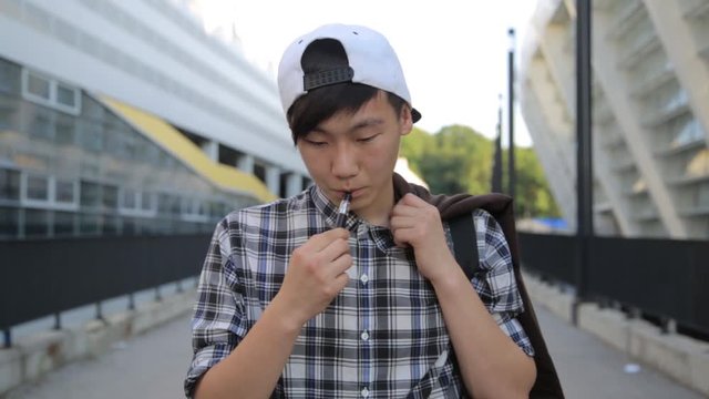 Young Man Walking On The Street And Smoke E-Cigarette. Vape.
