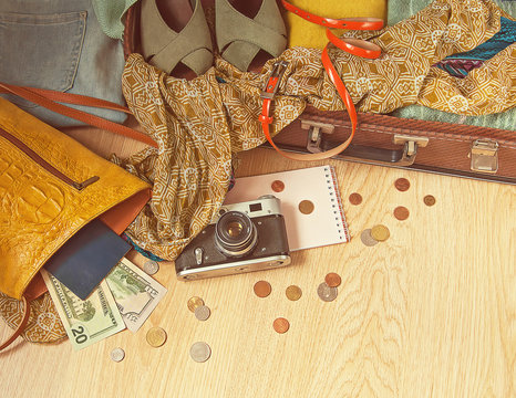 Preparation for a travel. Outfit of young woman in vintage style. Different objects on wooden surface. 